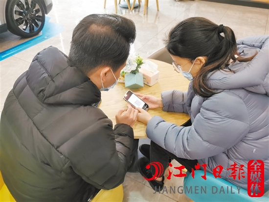 新能源汽车销售人员协助车主用手机进行投保新能源汽车险。